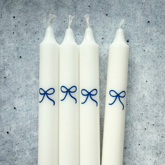blaue Schleifen auf weißer Stabkerze – Deko-Detail handgefertigter Kerzen von Wolkenreich
