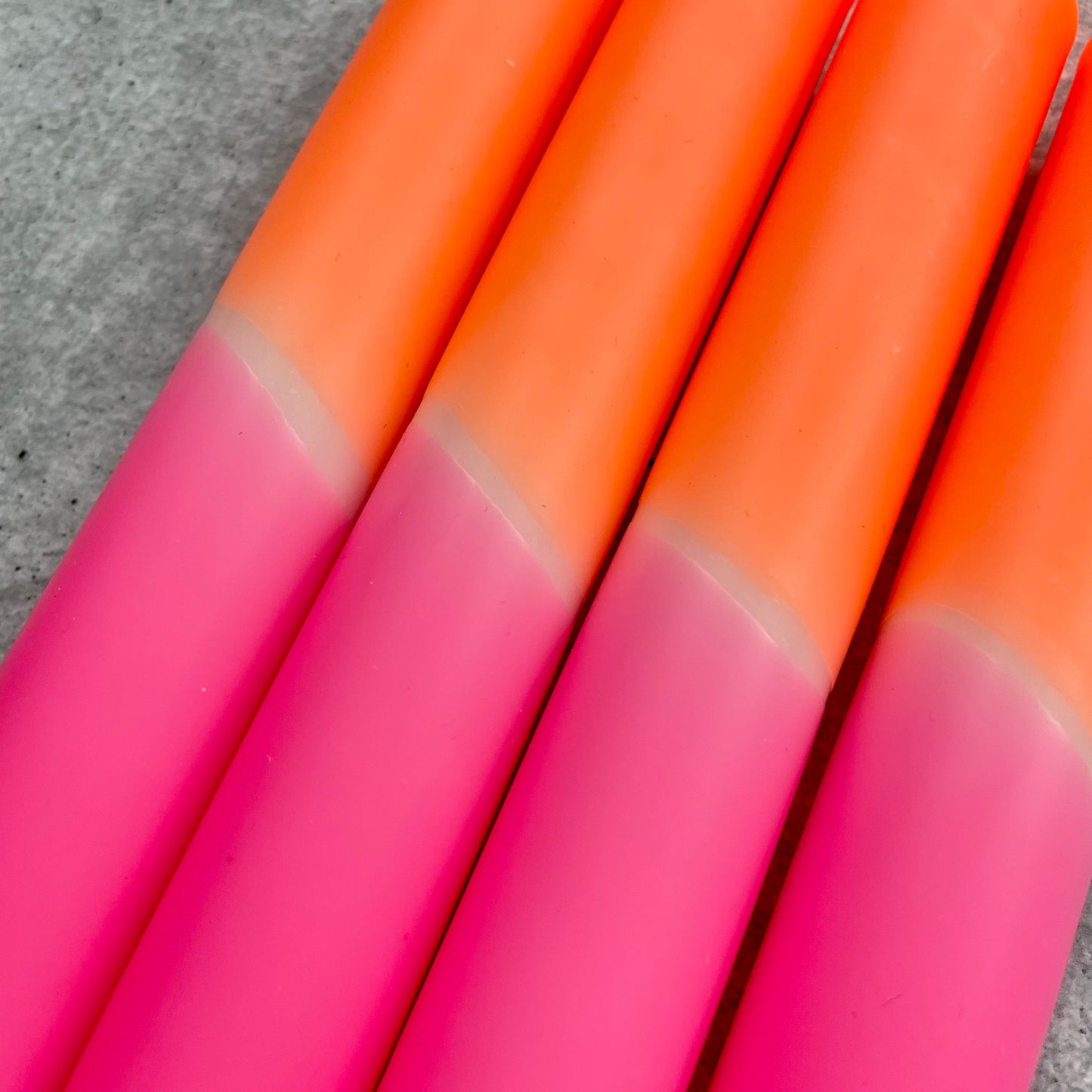 Nahaufnahme der Oberfläche einer Dip Dye Kerze in Neonpink und Neonorange