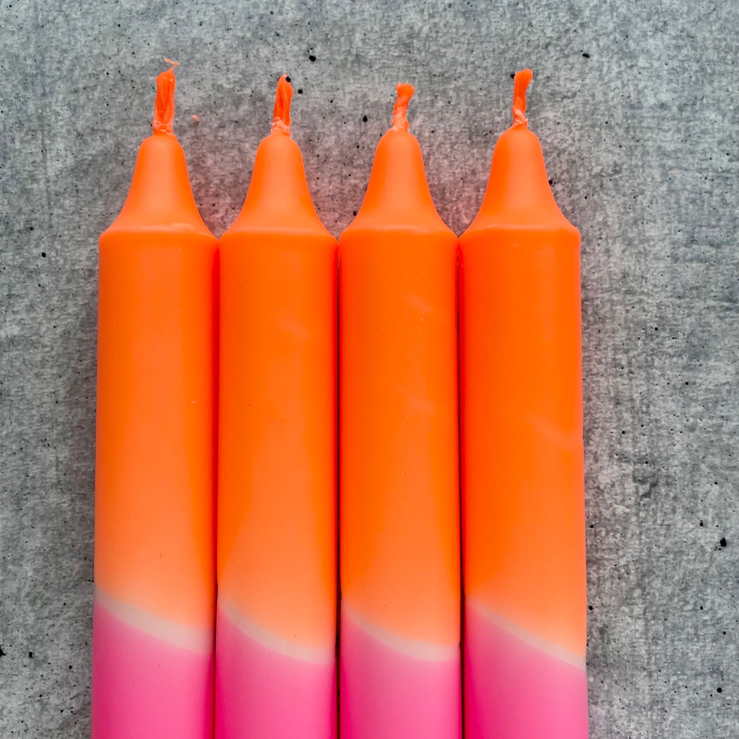 Detailaufnahme des lebhaften Farbverlaufs einer Dip Dye Kerze in Neonpink und Neonorange